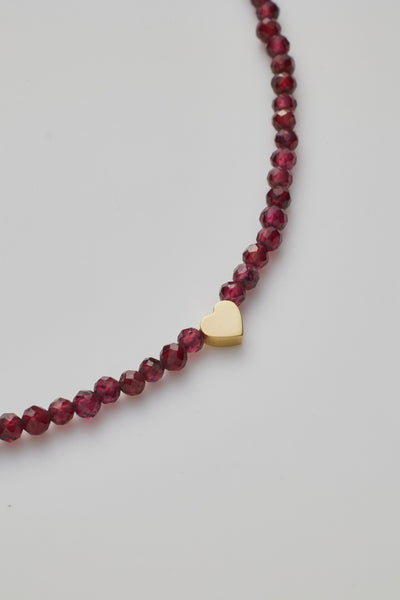 Close up showing small garnet red beads and gold heart 