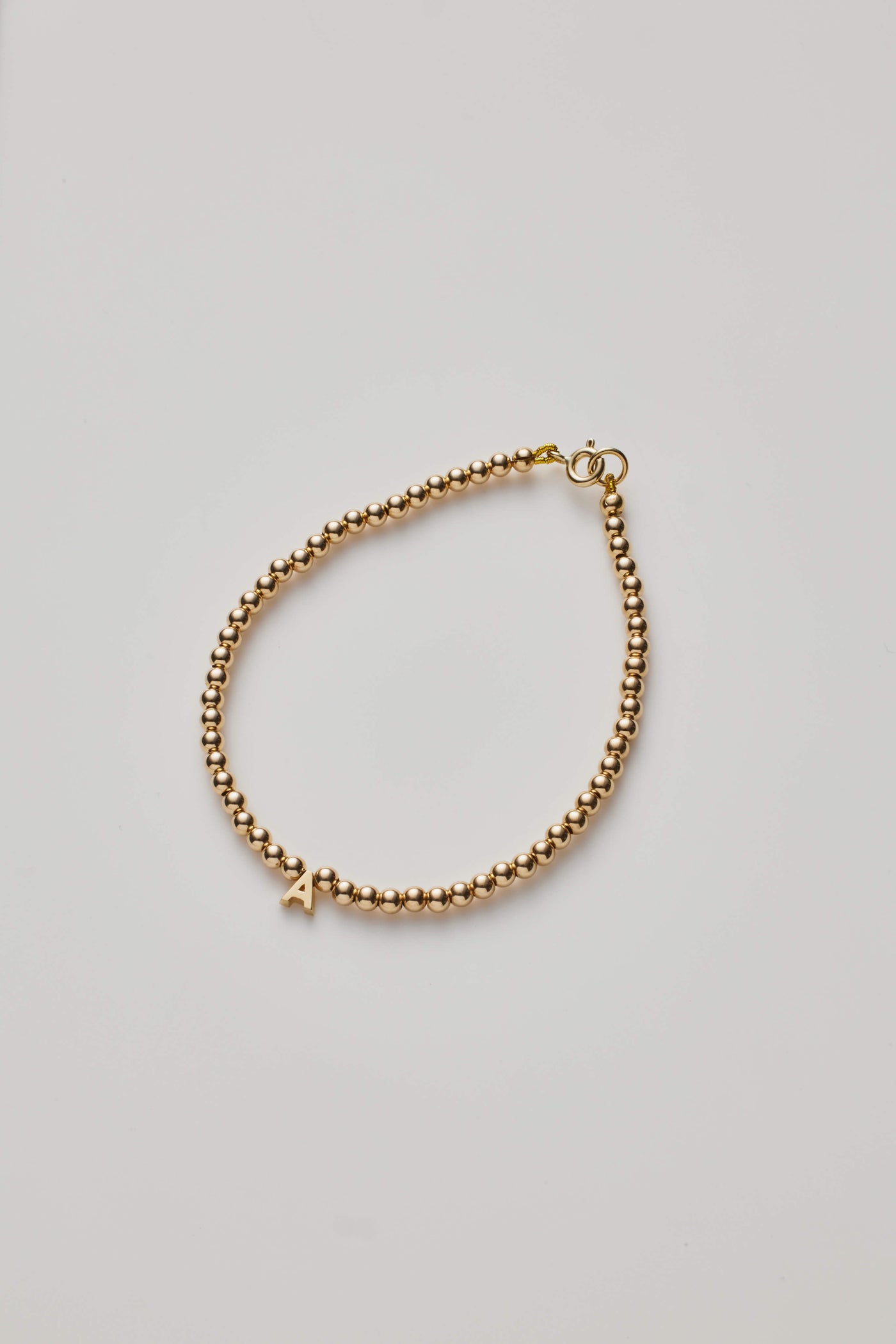 Gold beaded bracelet with gold letter charm A