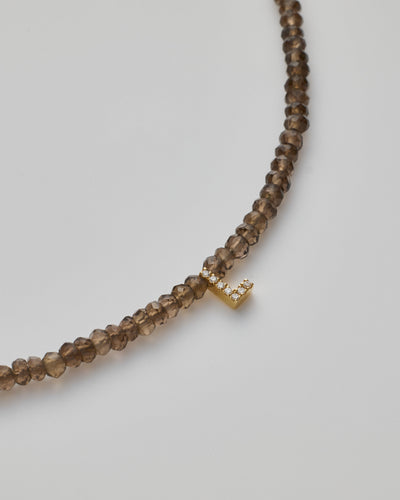 Delicate bracelet with smoky quartz  beads and a diamond alphabet charm, elegantly crafted.