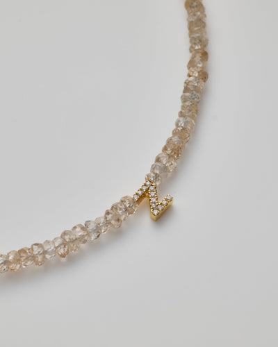 Delicate bracelet with natural zircon beads and a diamond alphabet charm, elegantly crafted.