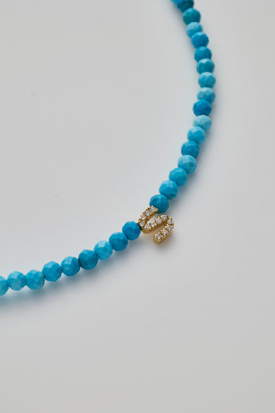 Delicate bracelet with Turquoise beads and a diamond alphabet charm, elegantly crafted.