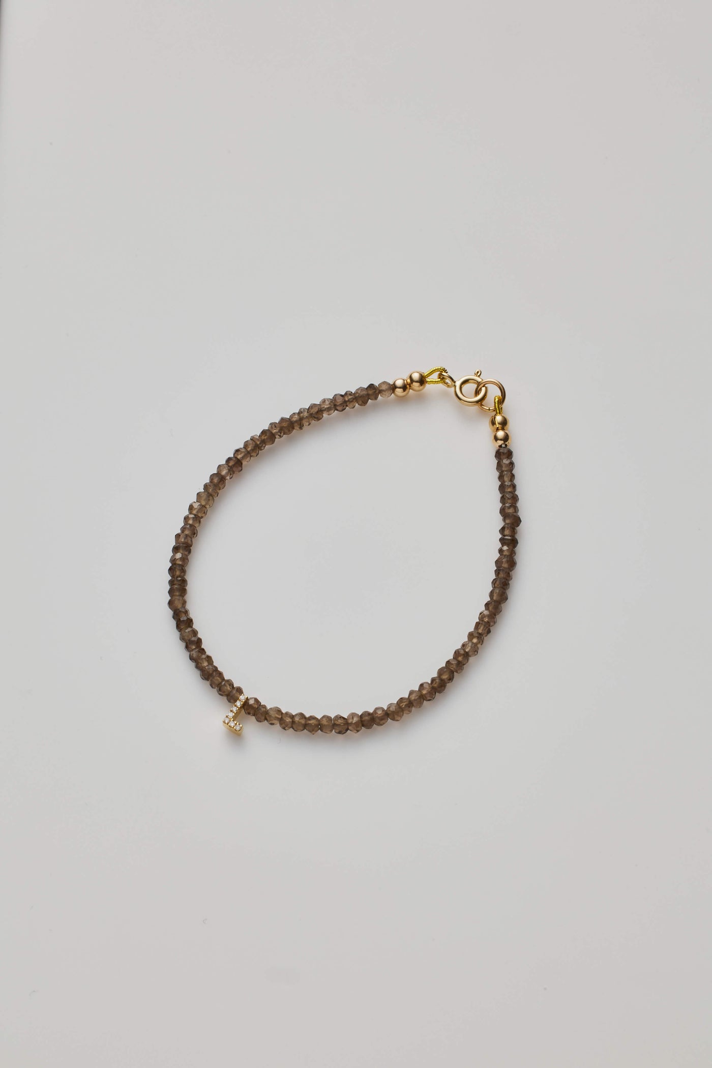 Delicate bracelet with smoky quartz  beads and a diamond alphabet charm, elegantly crafted.