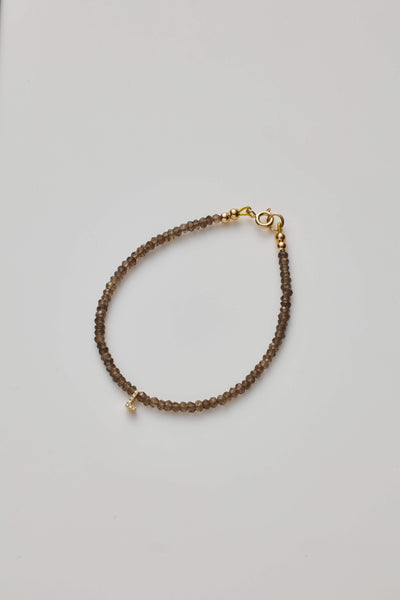 Delicate bracelet with smoky quartz  beads and a diamond alphabet charm, elegantly crafted.