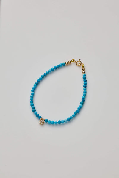 Delicate bracelet with Turquoise beads and a diamond alphabet charm, elegantly crafted.