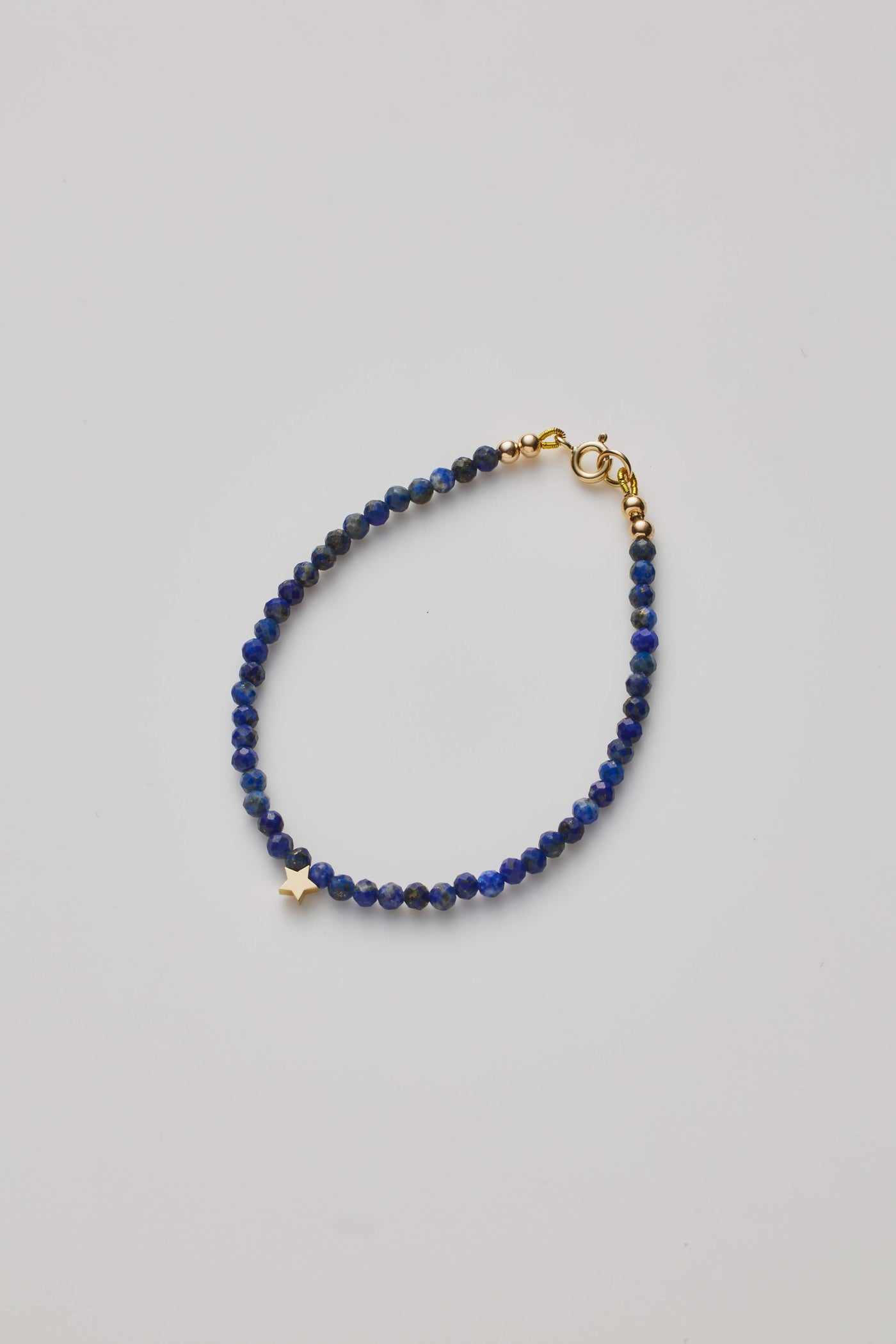 Delicate bracelet with Lapis lazuli beads and a gold star charm, elegantly crafted.