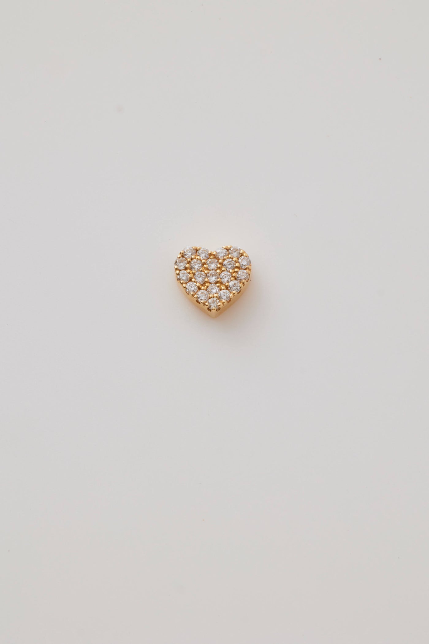 Gold heart-shaped pendant encrusted with sparkling diamonds arranged in a uniform pattern, covering the entire surface. The pendant exudes a luxurious and radiant appearance, set against a plain white background.