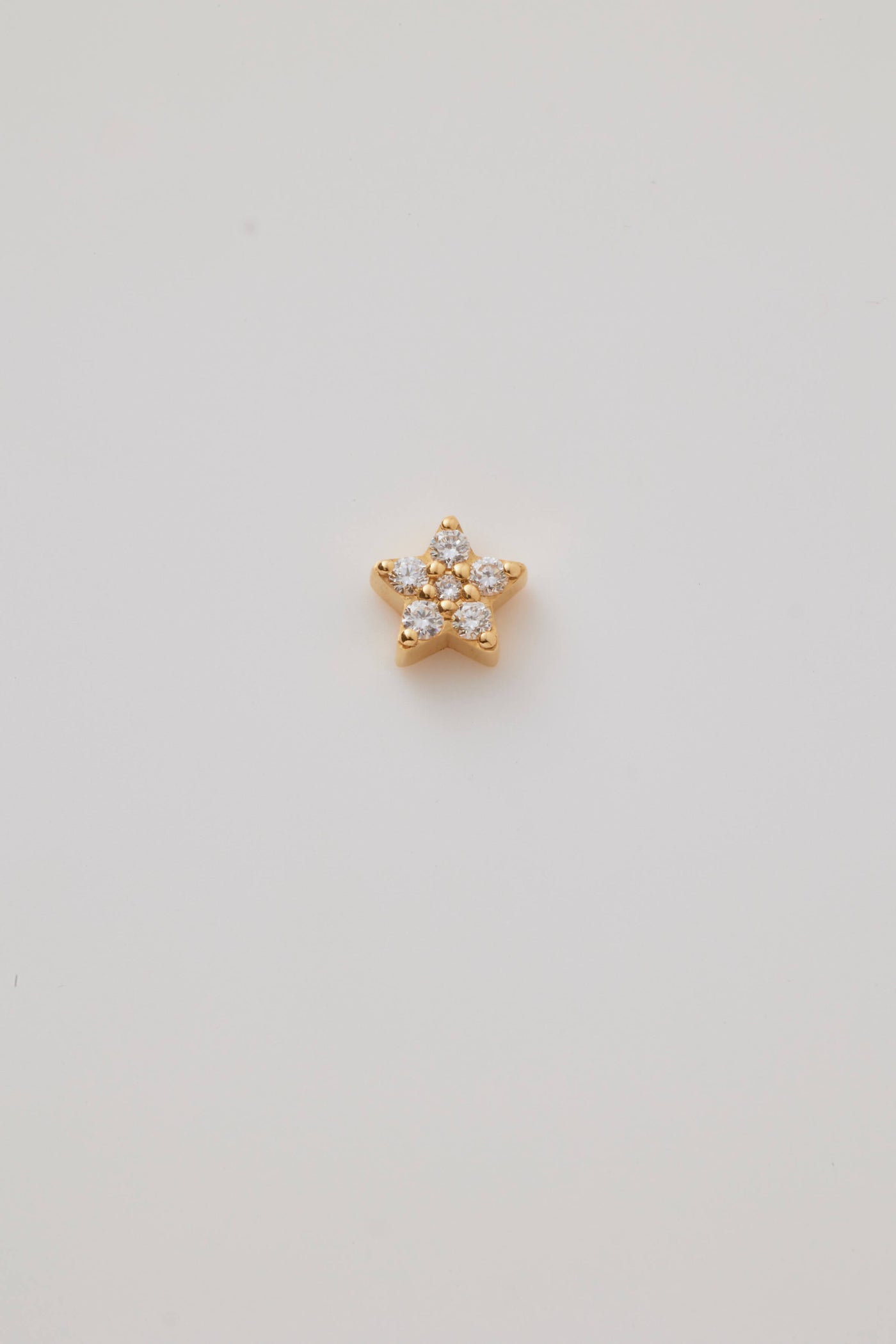 A solid gold star charm adorned with sparkling diamonds. The five-pointed star charm features brilliant-cut diamonds, creating a shimmering effect. A small hole at the top of the allows the charm to be threaded through with a necklace chain.