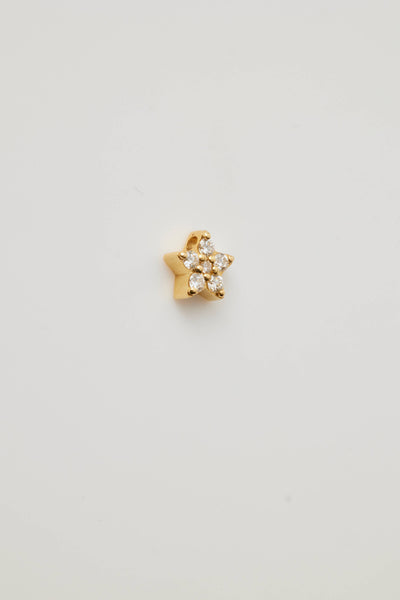 A side view showing a solid gold star charm adorned with sparkling diamonds. The five-pointed star charm features brilliant-cut diamonds, creating a shimmering effect. A small hole at the top of the allows the charm to be threaded through with a necklace chain.