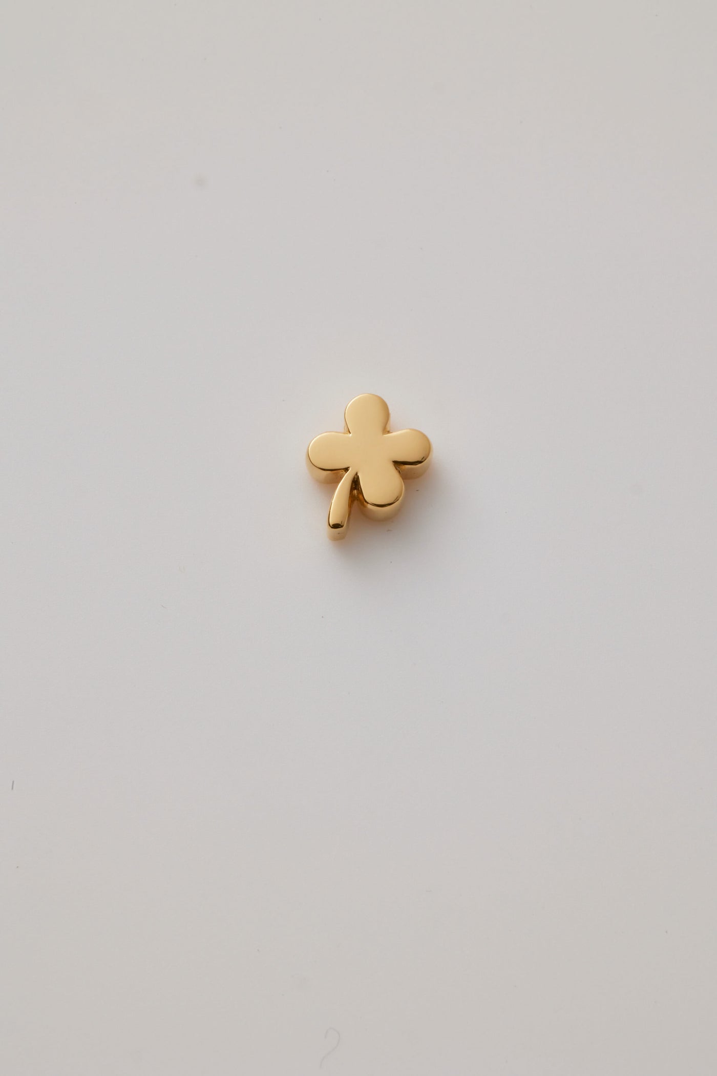 Reversed side of a polished gold four-leaf clover charm with smooth, rounded leaves. A symbol of luck, perfect for any chain or bracelet.