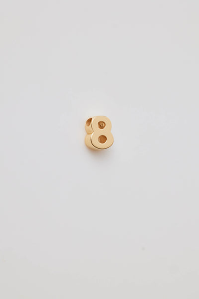 Three-dimensional number charms, each representing a number from 0 to 9, crafted from 18-karat solid gold. Each charm has a sleek, polished surface that radiates a rich, golden glow, adding a touch of luxury. A small hole is integrated at the top of each charm for easy attachment to a chain or bracelet. 