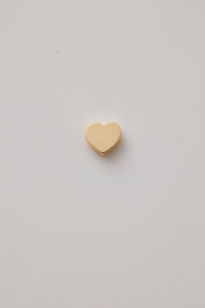 A front view of a gold heart charm made from polished 18-karat gold. The charm features a classic heart shape with a sleek, smooth finish and a precise hole through the centre, designed for threading a gold chain. 