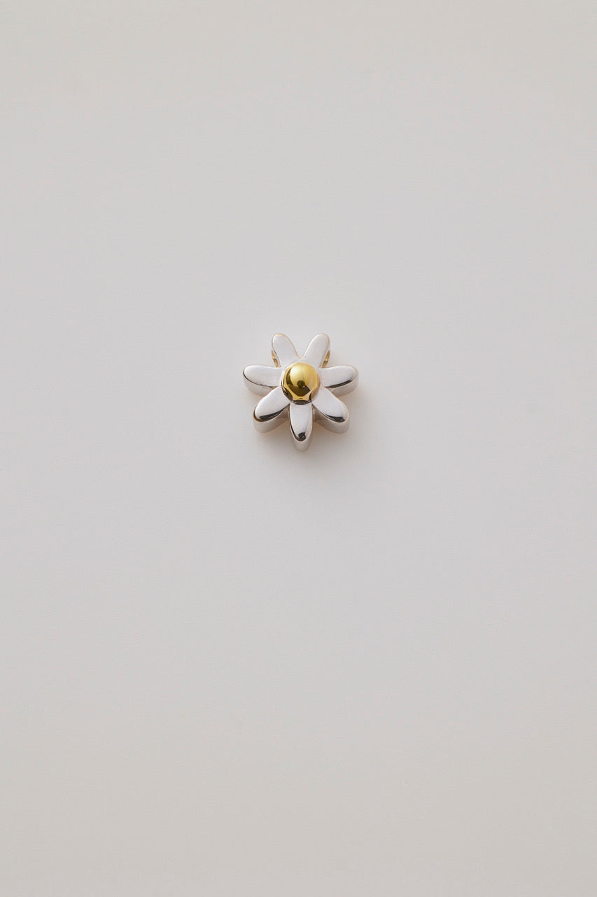 A three-dimensional daisy charm crafted in polished gold. The charm showcases delicate, detailed petals radiating from a textured centre, capturing the beauty of a blooming flower. 