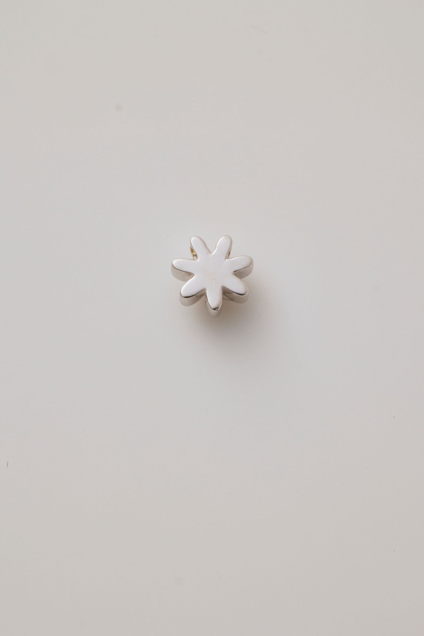 Back reverse view of a white gold three-dimensional daisy charm with detailed petals.