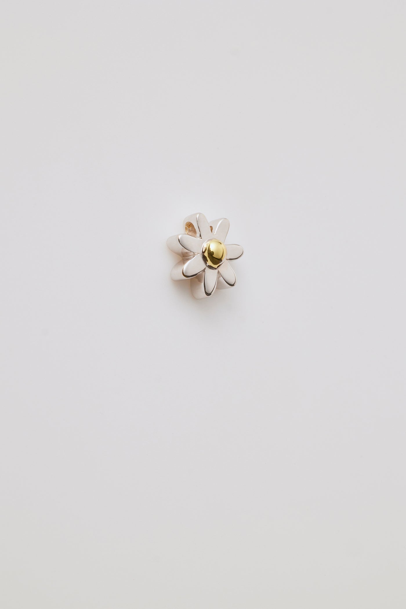 A gold three-dimensional daisy charm with detailed petals and a centre hole for threading a chain. Elegant and versatile.