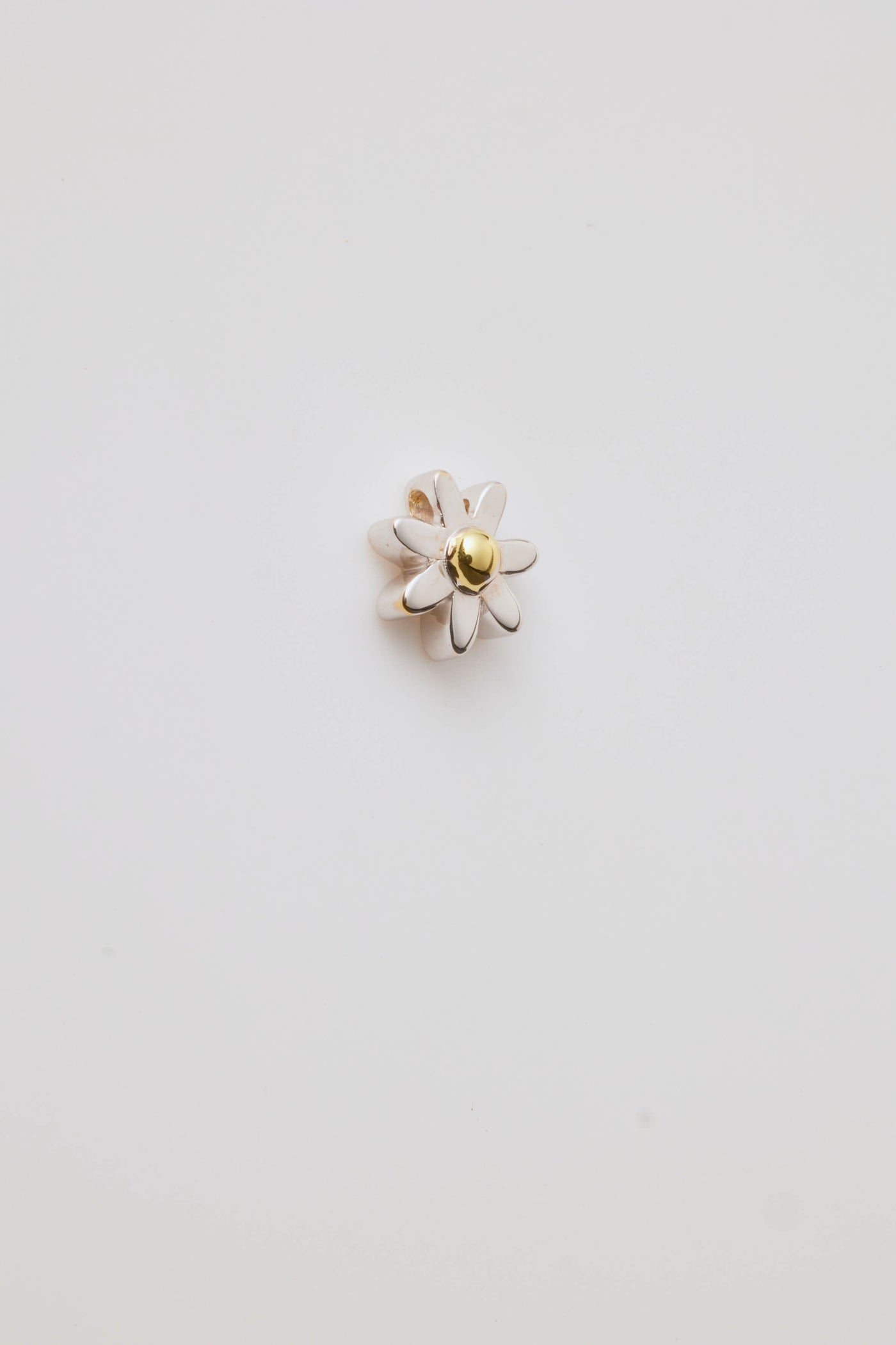 A gold three-dimensional daisy charm with detailed petals and a centre hole for threading a chain. Elegant and versatile.