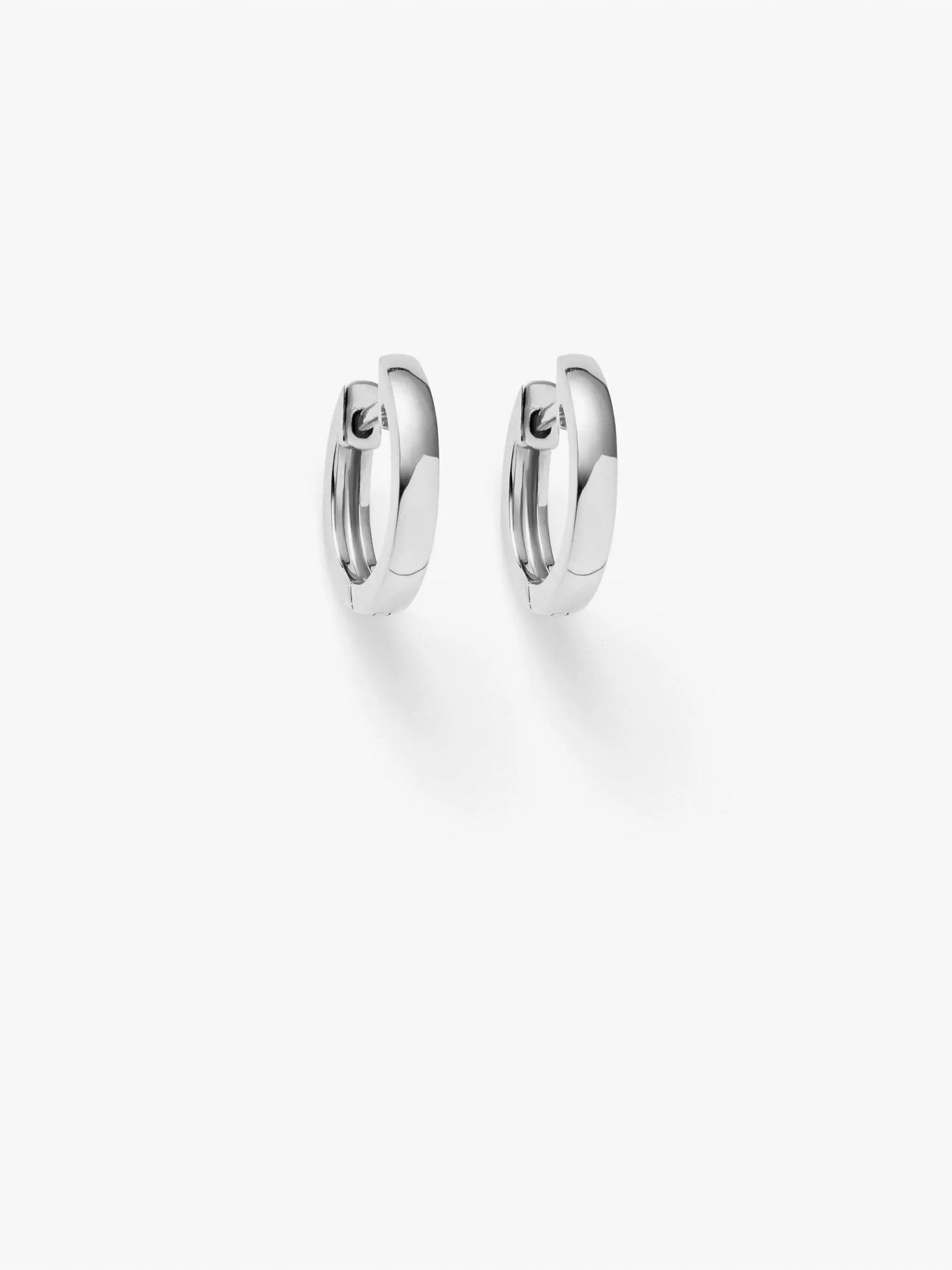 Product Description: Presenting the Huggie Earrings in 18k White Gold against a pristine white background. These earrings boast a sleek and polished surface, perfectly highlighting their slightly rounded shape and 8mm diameter. Simple yet elegant, they are ideal for both casual and formal occasions.