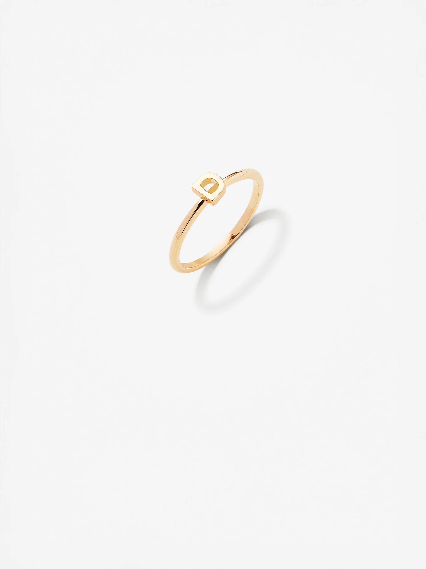 The Letter D Ring in 18k gold featuring a minimalist design with a simple rectangular accent on a plain white background.