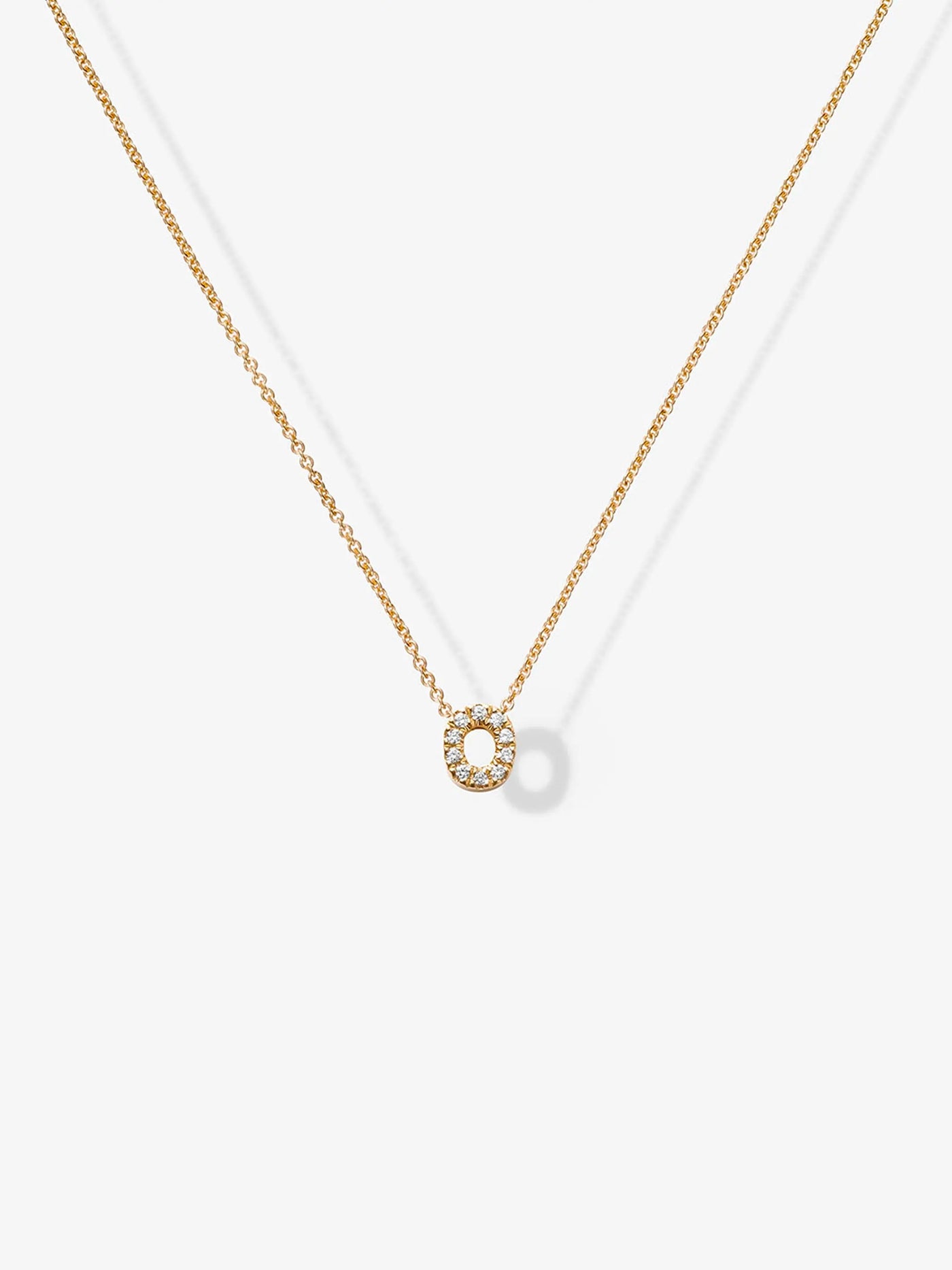 A sophisticated Letter O Necklace in Diamonds and 18k Gold features a delicate 18k gold chain with a small, circular pendant encrusted with tiny diamonds. The pendant boasts an open circle design, elegantly highlighted against a plain white background in the photograph.