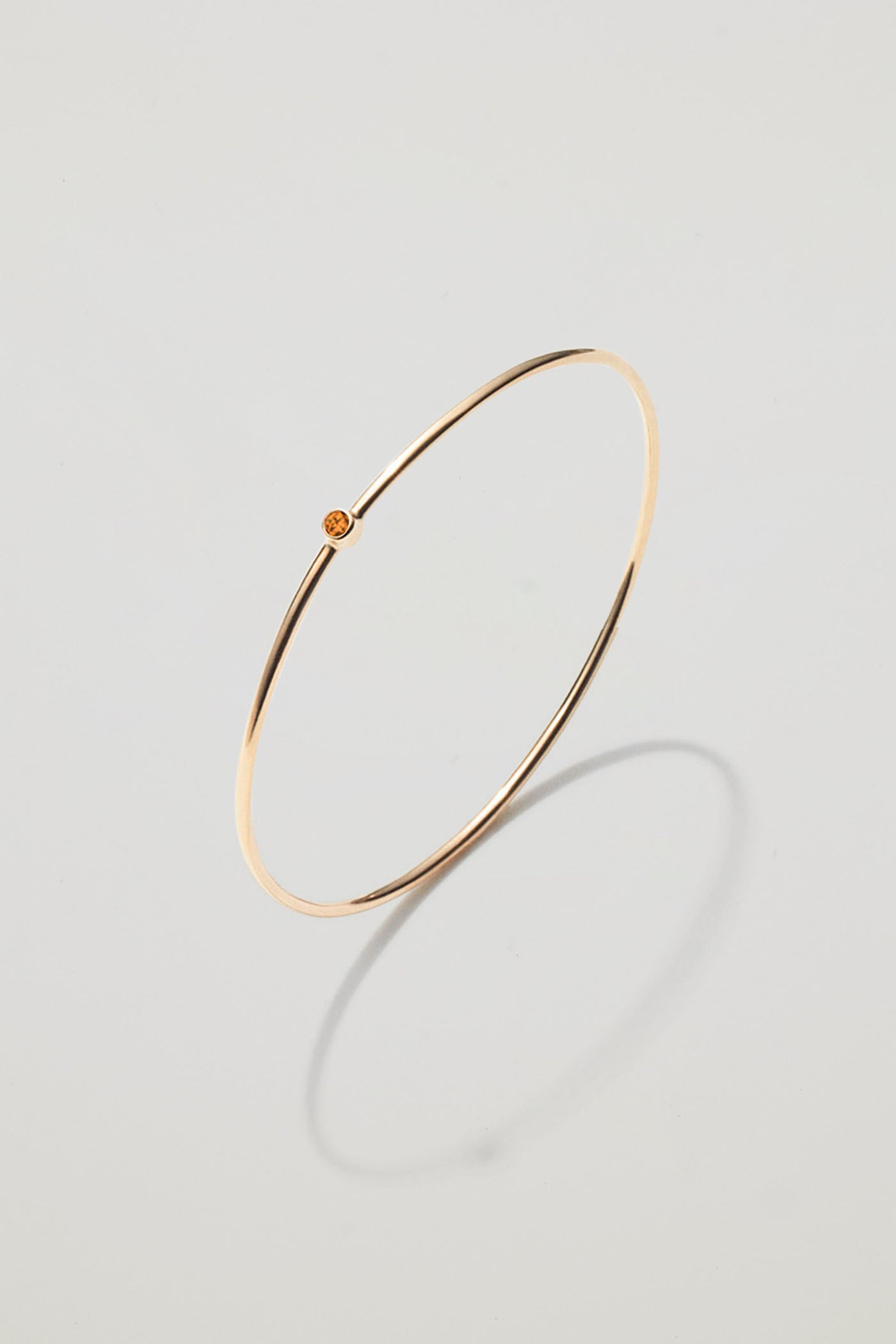 Solid gold bangle with a November citrine birthstone, symbolising joy and abundance.