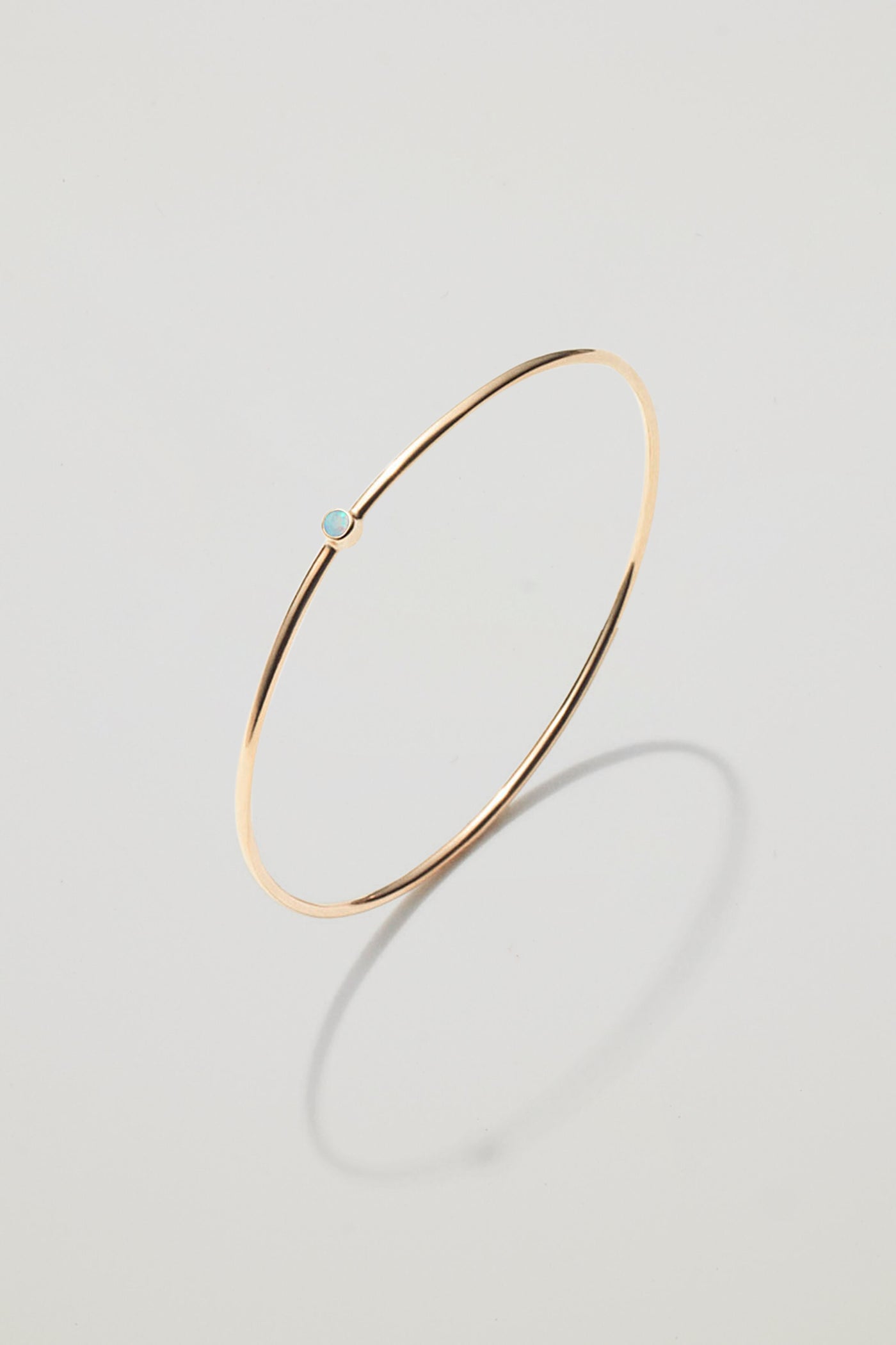 Solid gold bangle with an October opal birthstone, symbolising hope and creativity.