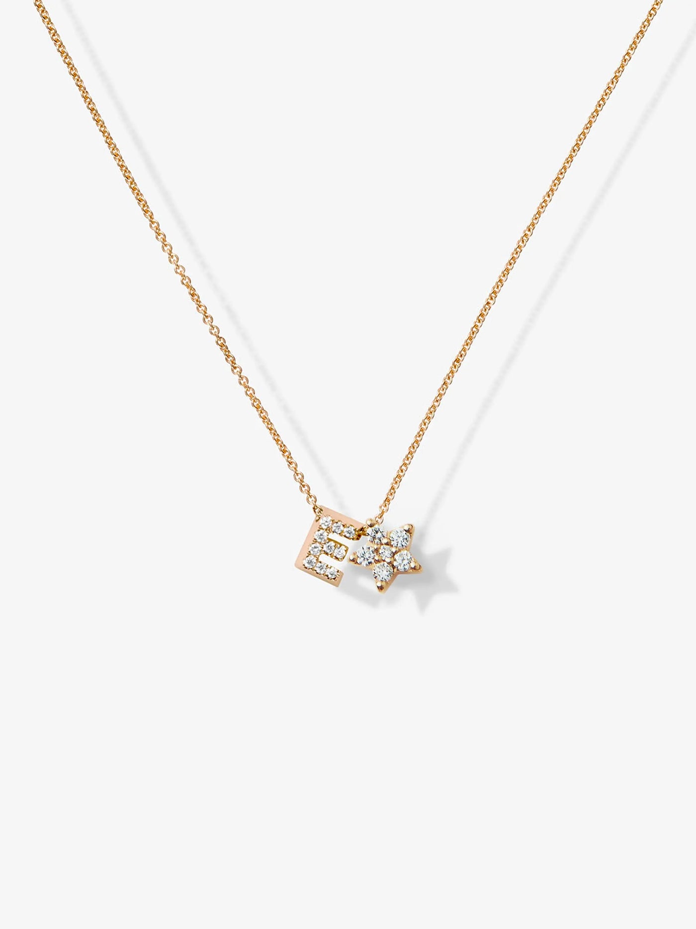 The One Letter and Star Necklace in Diamonds and 18k Gold features a delicate 18k solid gold chain with a unique pendant shaped like an outline of a shooting star. The pendant is adorned with small, sparkling diamonds, positioned off-center to the right, enhancing the charm of this fine and elegant piece.