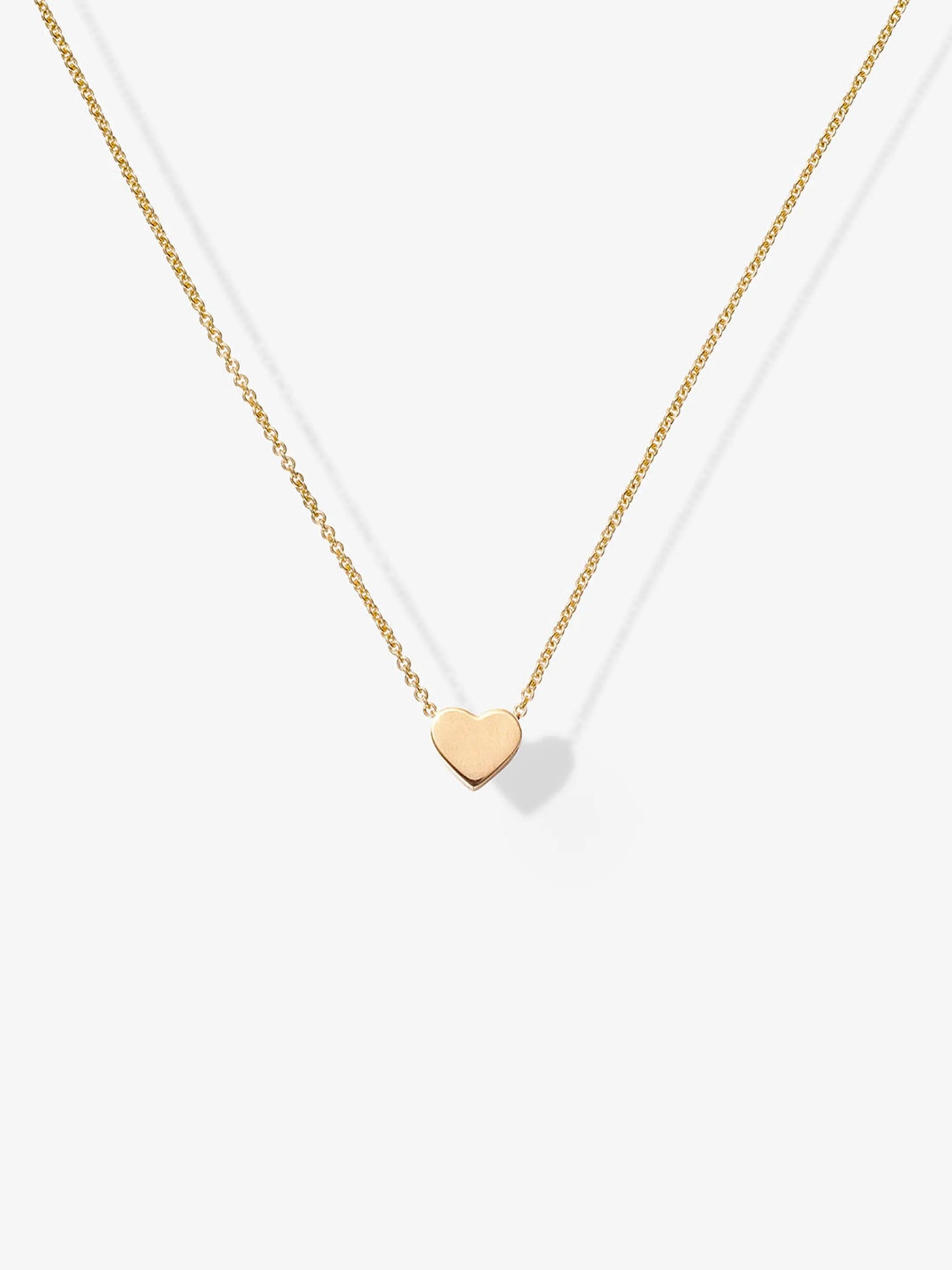 The One Heart 18-Karat Gold Necklace is a delicate piece crafted from high-quality gold, featuring a thin, adjustable chain and a small, flat heart-shaped pendant at its center. Displayed on a plain white background, the necklace's simple and elegant design is beautifully highlighted.