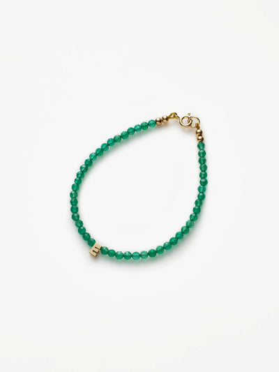 An elegant One Letter Bracelet in Green Onyx and 18k Gold features uniformly sized, round beads with gold accents, a gold clasp, and a small rectangular charm. The clean and sophisticated design stands out elegantly against a plain white background. Custom sizes are available to ensure the perfect fit.