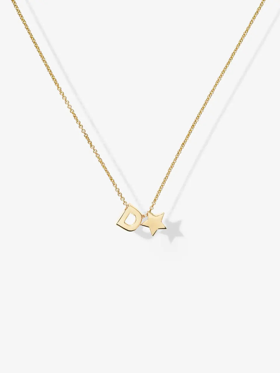 The One Letter and Star Necklace in 18k Gold features a delicate gold chain with two charms: a capital letter 'D' and a small star. Both charms, crafted from 18k solid gold, hang elegantly close together in the center against a plain white background, highlighting the necklace's refined beauty.