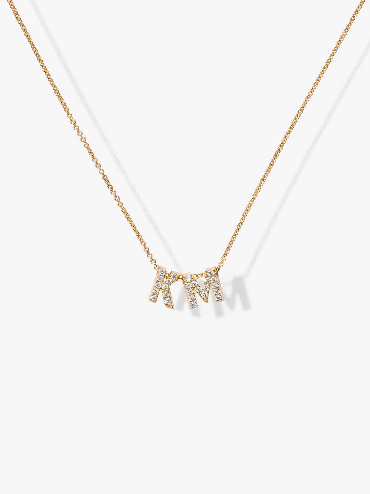 A delicate 18k solid gold necklace featuring two small, capital letter charms encrusted with diamonds. This stunning Two Letters Necklace in Diamonds and 18k Gold is displayed against a plain white background.