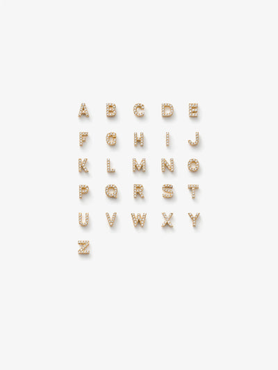 
A grid of 18k solid gold and diamond alphabet letters. The letter charms set with sparkling diamonds are arranged in alphabetical order on a white background from A to Z.