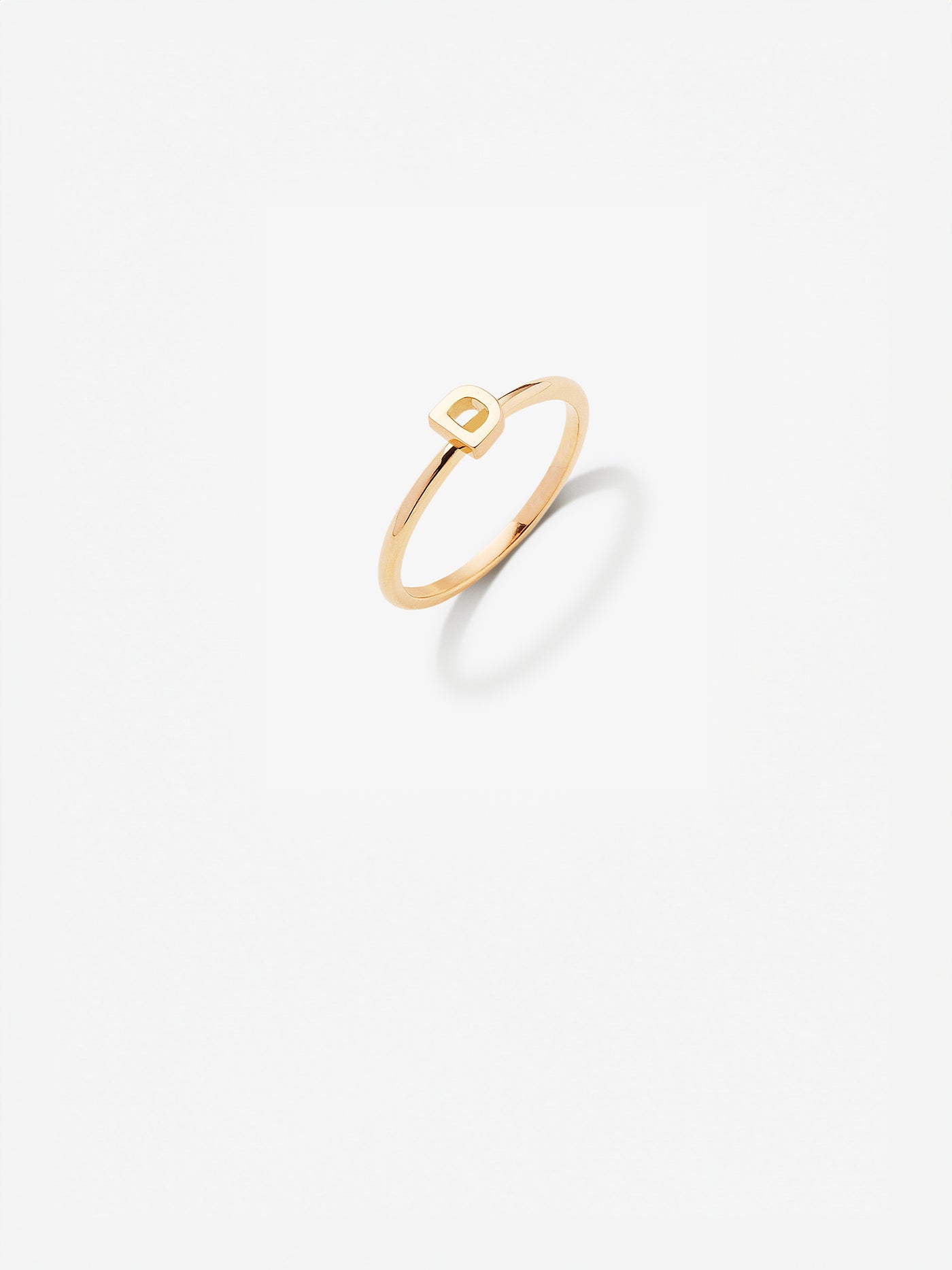 The Letter D Ring in 18k gold featuring a minimalist design with a simple rectangular accent on a plain white background.