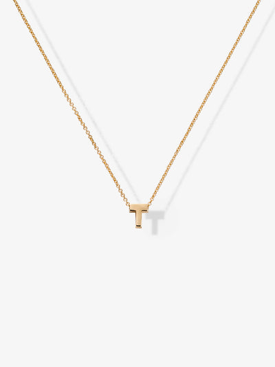 The Letter T Necklace in 18k Gold showcases a small, capital letter "T" pendant, elegantly suspended in the center of a fine chain. Its minimalist design and delicate 18k gold construction offer a modern and elegant look against the plain white background.