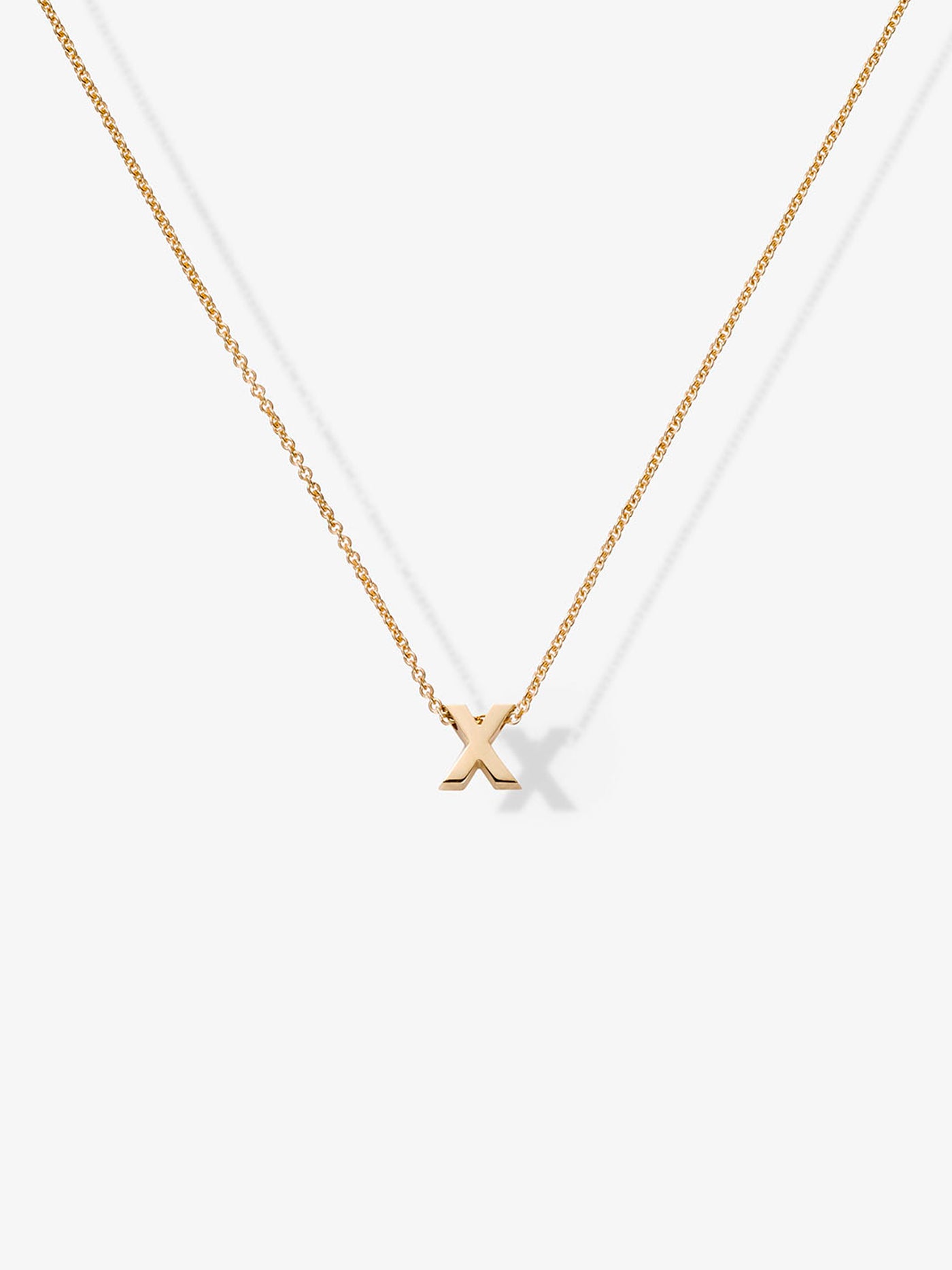 The Letter X Necklace in 18k Gold features a delicate 18k solid gold chain and a small, gold "X" pendant. The plain white background highlights the simplicity and elegance of the necklace.