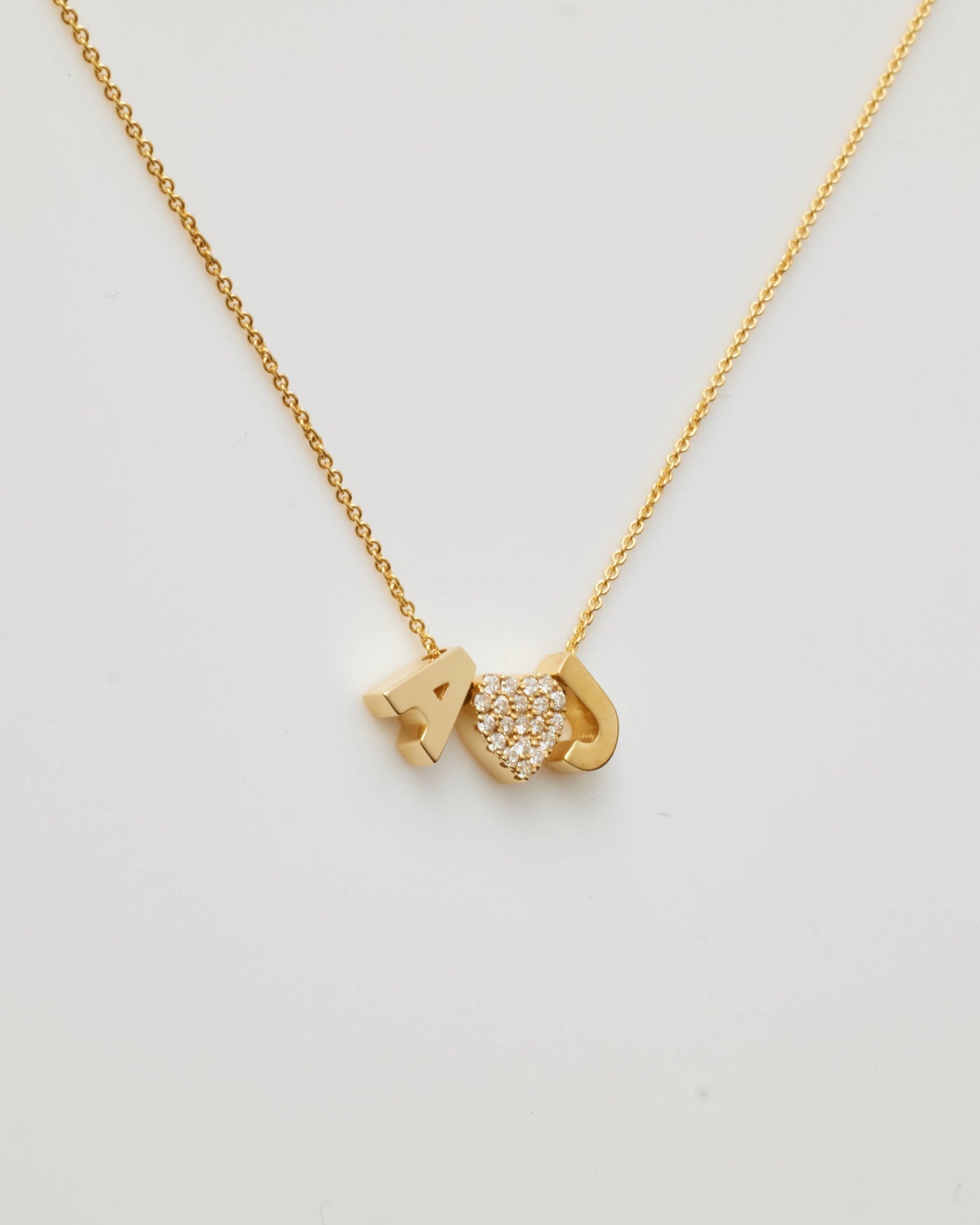 Small gold polished letter charms 'A' and 'J' paired with a diamond heart charm, threaded onto a delicate necklace chain.