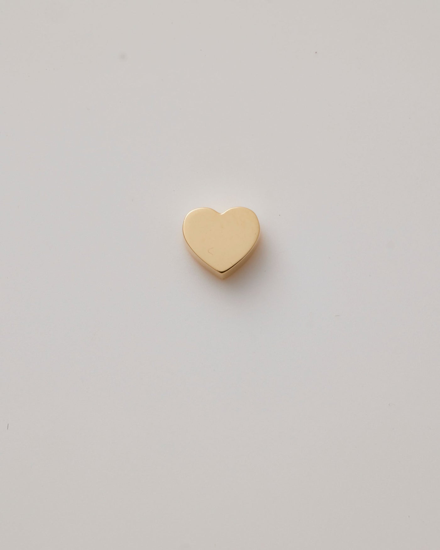 Small solid gold heart charm with a polished finish, designed to slide onto a necklace chain for customisable jewellery.