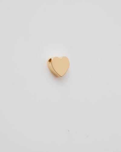 Small solid gold heart charm with a polished finish, designed to slide onto a necklace chain for customisable jewellery.