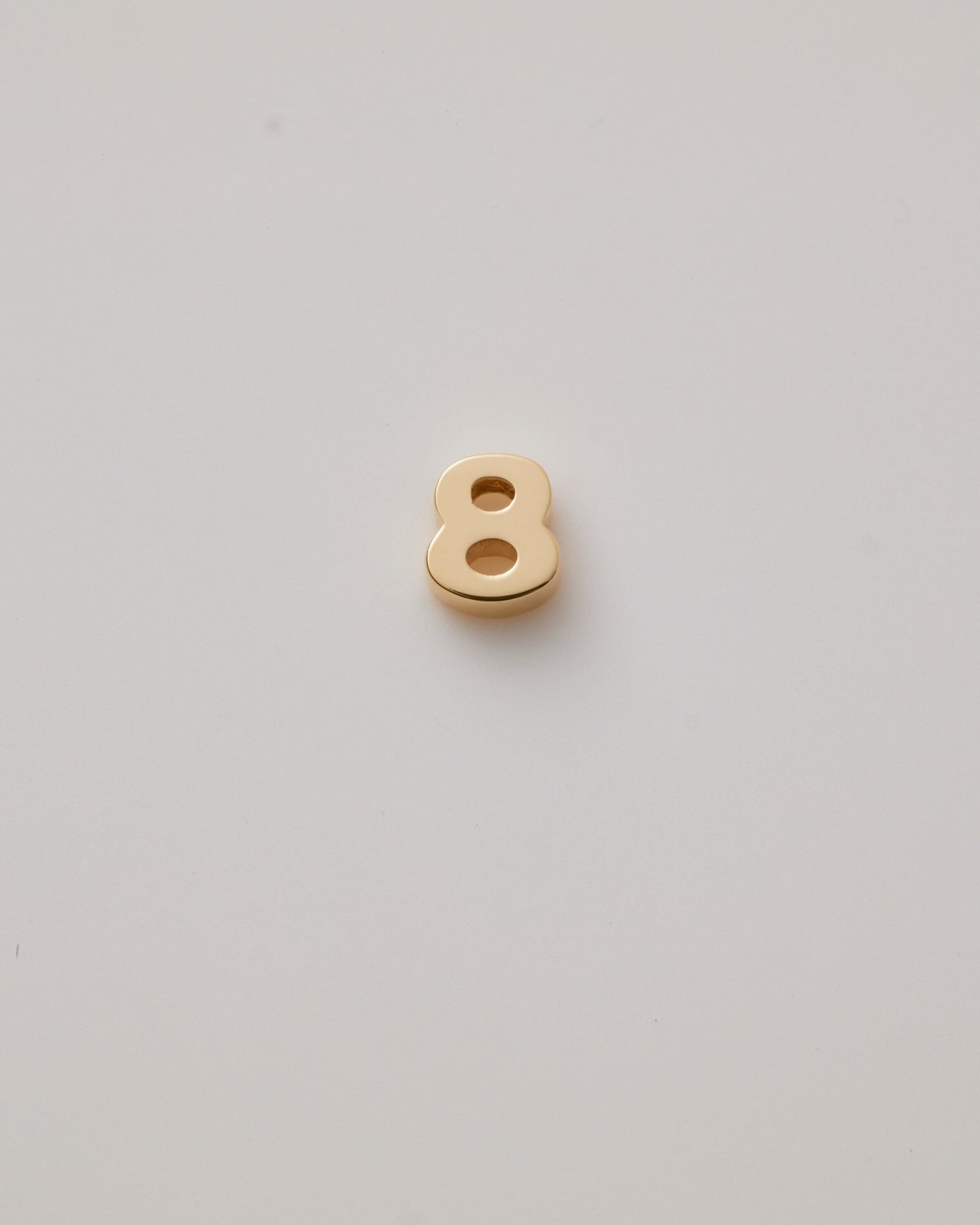 Small solid gold number charms (0-9), designed to slide onto a necklace chain for a personalised jewellery piece with symbolic meaning.