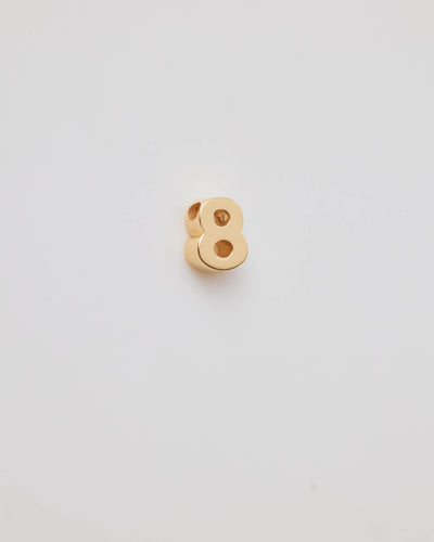 Small solid gold number charms (0-9), designed to slide onto a necklace chain for a personalised jewellery piece with symbolic meaning.