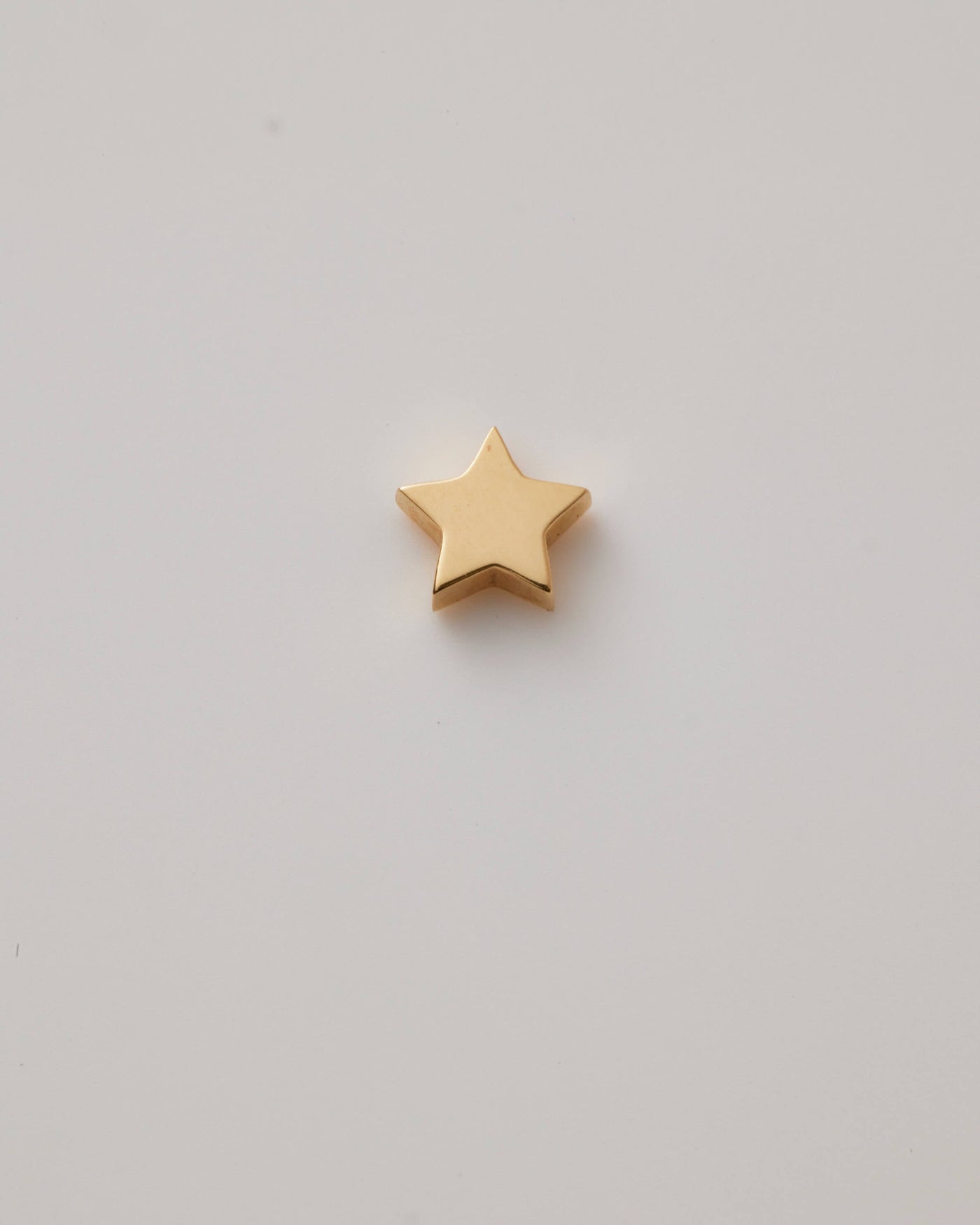 Polished solid gold star charm, a symbol of remembrance and love.