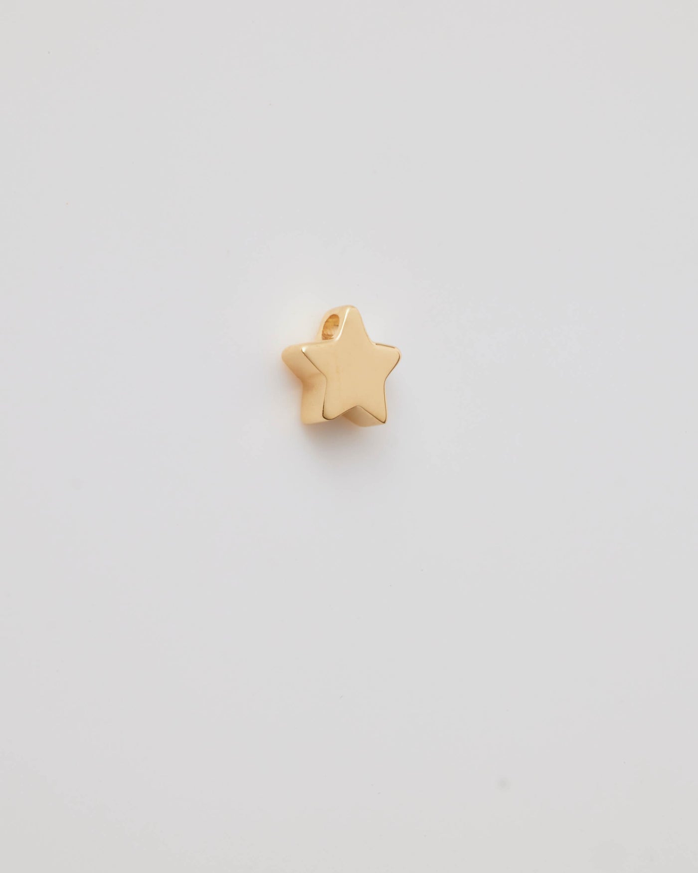 Polished solid gold star charm, a symbol of remembrance and love.
