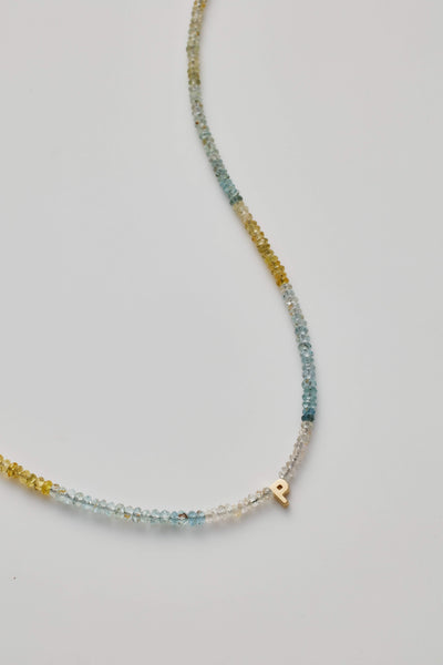 14K gold letter P necklace strung with naturally shaded aquamarine gemstones, showcasing ocean-inspired hues.