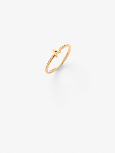 Close-up image of a personalised A  gold ring adorned with intricate, miniature dimensional letters from the alphabet on a light grey background 